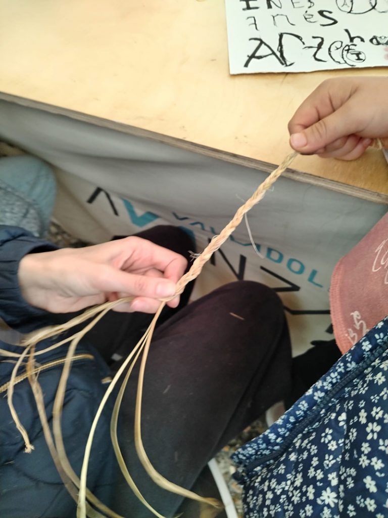 Persona aprendiendo a trenzar fibras vegetales en un taller de cestería artesanal en Valladolid.